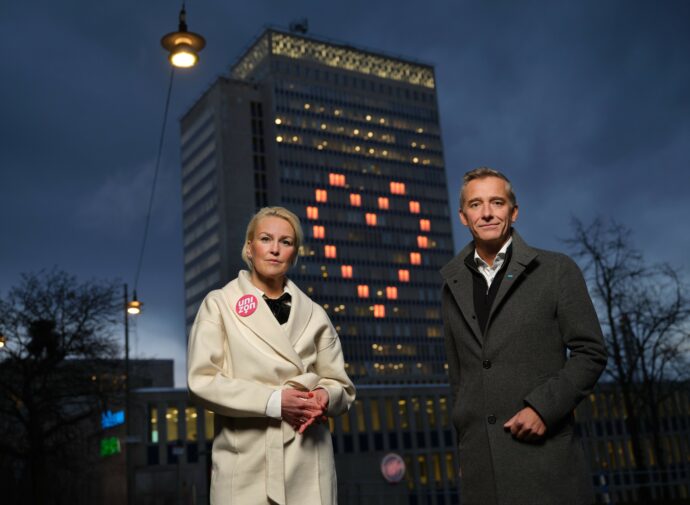 Olga Persson och Jens Wikström framför Folksamskrapan som lyser upp med ett stort hjärta.